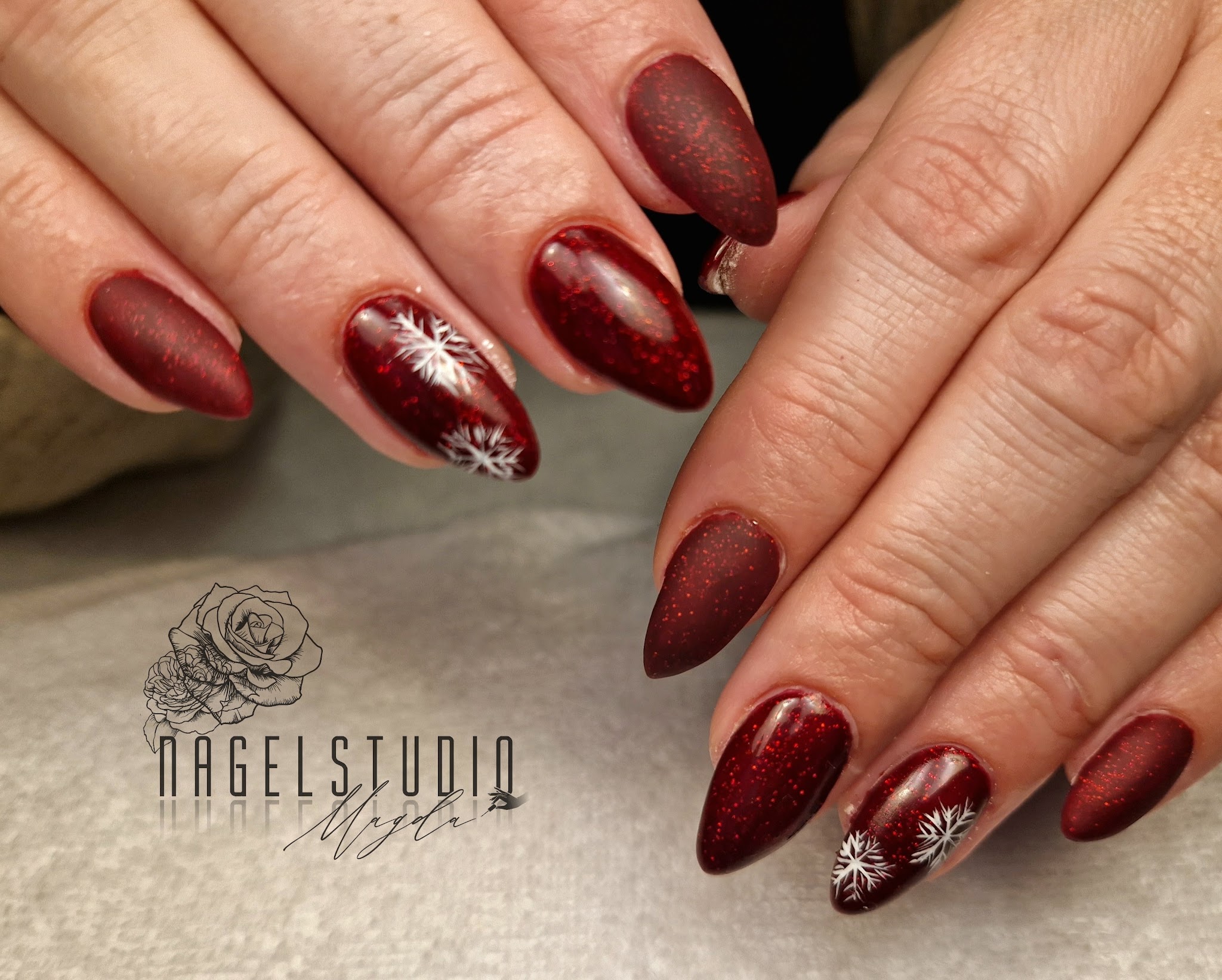 Bordeauxrode nagels met fijne witte versieringen, werk van Nagelstudio Magda