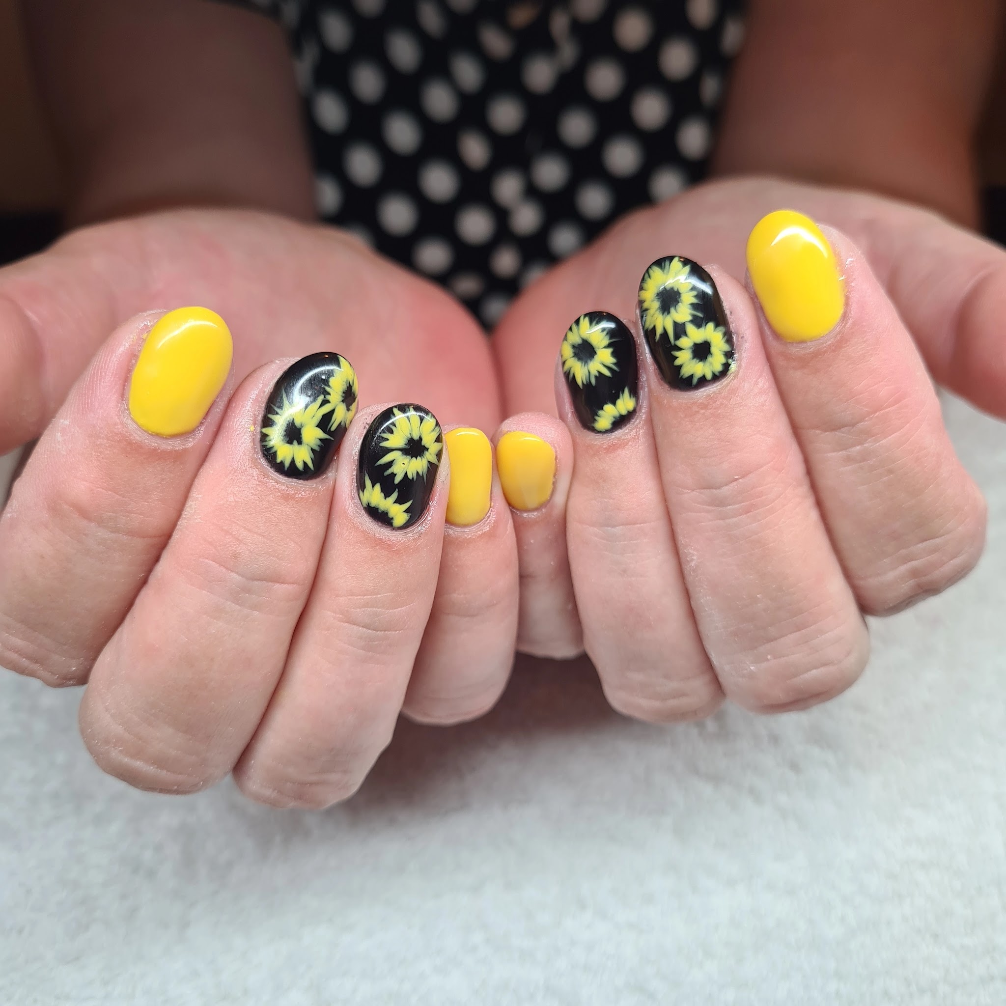 Gele nagels met zonnebloemmotieven op een donkere basis